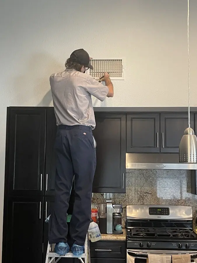 Technician inspecting an air vent during HVAC service in Ontario